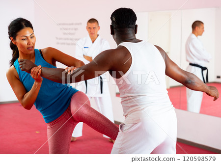 Men and woman training self-protection martial arts in gym Men and woman training self-protection martial arts in gym 120598579
