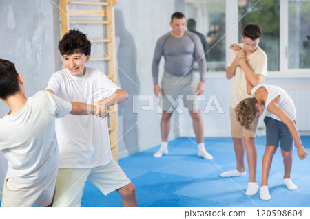 Diligent preteen student practicing self-defense techniques in pairs 120598604