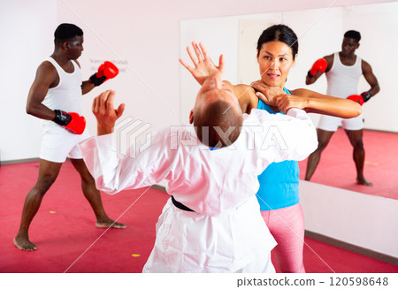 Woman exercising self defence moves with trainer, man boxing in gym Woman exercising self defence moves with trainer, man boxing in gym 120598648