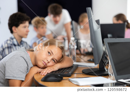 Tired preteen girl sleeping at computer table in training room Tired preteen girl sleeping at computer table in training room 120598672