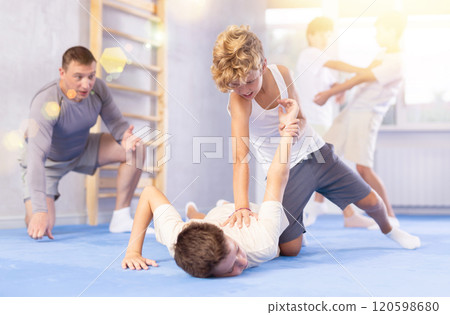 Diligent preteen student twisting his opponent's arm on the floor 120598680