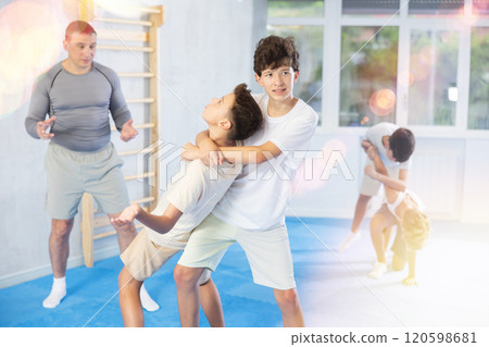 Sporty boys are practices self-defence moves in pairs doing throw over shoulder in sports studio Sporty boys are practices self-defence moves in pairs doing throw over shoulder in sports studio 120598681