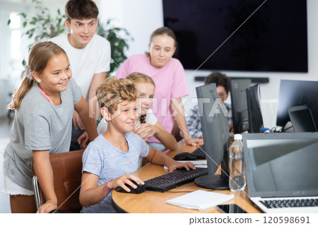 Preteen boys and girls working on computer together with teacher in IT cabinet 120598691
