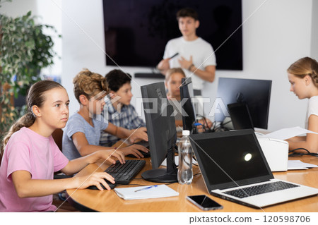 Preteen girl working with computer programs in training room 120598706