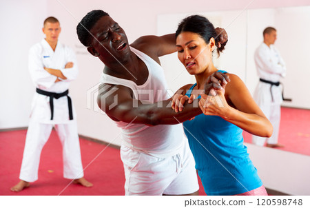 People training martial arts in gym with trainer People training martial arts in gym with trainer 120598748