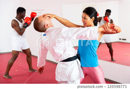 Sporty woman with a trainer conducts painful reception on the eyes in gym Sporty woman with a trainer conducts painful reception on the eyes in gym 120598771