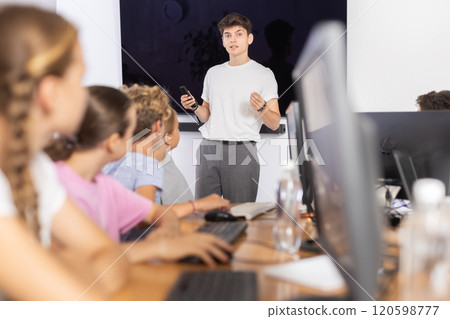 Guy teacher teaches group of students in computer class Guy teacher teaches group of students in computer class 120598777