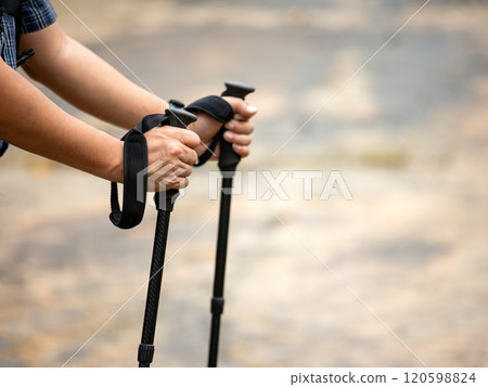 Close-up of hiker use both hands holding trekking poles during hike on rural trail, outdoor adventure and gear with copy space 120598824
