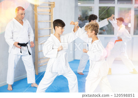 Diligent preteen attendee of karate classes fighting with his opponent in sports hall Diligent preteen attendee of karate classes fighting with his opponent in sports hall 120598851
