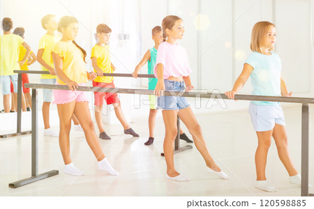 Preteen girls practicing ballet positions near bar in choreographic school Preteen girls practicing ballet positions near bar in choreographic school 120598885