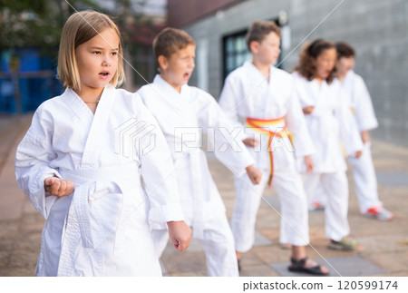 Young children in kimono perform techniques karate on city street 120599174