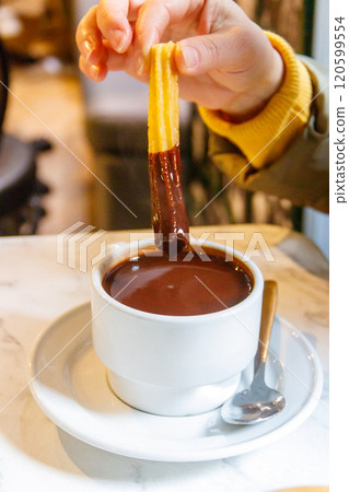 Dipping churros into hot chocolate mug. Churros - traditional spanish dessert 120599554