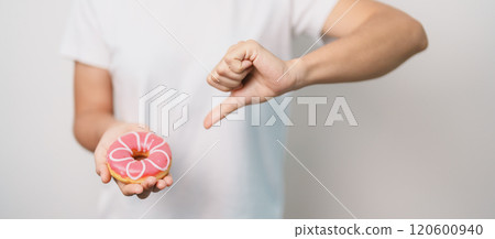 woman hand hold pink Donut, choose stop eating sweet is Unhealthy ealthy food. Dieting control, Weight loss, Obesity, eating lifestyle and nutrition concepts woman hand hold pink Donut, choose stop eating sweet is Unhealthy ealthy food. Dieting control, Weight loss, Obesity, eating lifestyle and nutrition concepts 120600940