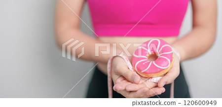 woman hand hold Donut with tape measure, choose stop eating sweet is Unhealthy ealthy food. Dieting control, Weight loss, Obesity, eating lifestyle and nutrition concepts woman hand hold Donut with tape measure, choose stop eating sweet is Unhealthy ealthy food. Dieting control, Weight loss, Obesity, eating lifestyle and nutrition concepts 120600949