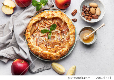 Delicious homemade apple galette with almond petals, honey, and fresh mint on grey table 120601441