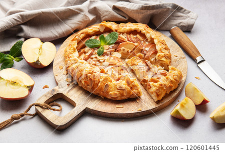 Delicious homemade apple galette with almond flakes and fresh mint on rustic wooden board Delicious homemade apple galette with almond flakes and fresh mint on rustic wooden board 120601445