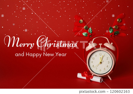 Merry Christmas and New Year, pink alarm clock and decorative deer antlers on a red background with text 120602163