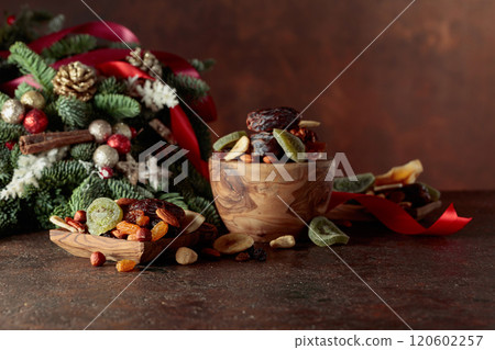 Dried fruits and nuts with Christmas wreath on a brown vintage table. 120602257