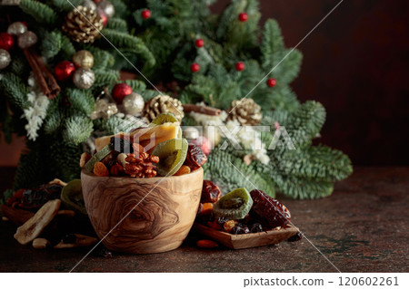 Dried fruits and nuts with Christmas wreath on a brown vintage table. 120602261