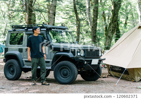Male camper standing in front of his car (car, RV, SUV) at an auto campsite Male camper standing in front of his car (car, RV, SUV) at an auto campsite 120602371