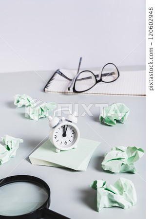 Alarm clock on writing paper, notepad and glasses on desk, burnout breaks concept vertical view 120602948