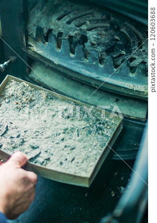 A man cleaning a pellet stove with a brush. Maintenance concept. High quality photo A man cleaning a pellet stove with a brush. Maintenance concept. High quality photo 120603688