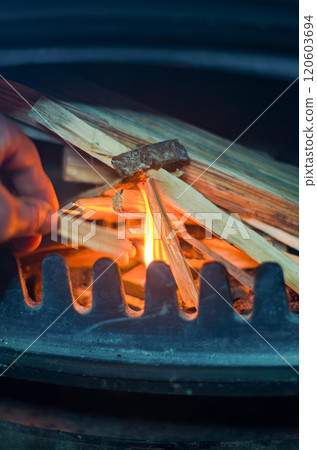 male hand holds a matchstick, ready to ignite the firewood in a fireplace. High quality photo 120603694