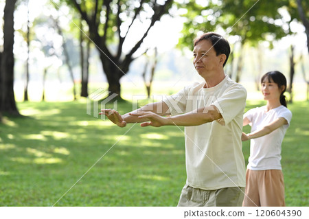 Elder man and young woman practicing Tai Chi in a serene park. Mindfulness and wellbeing concept 120604390