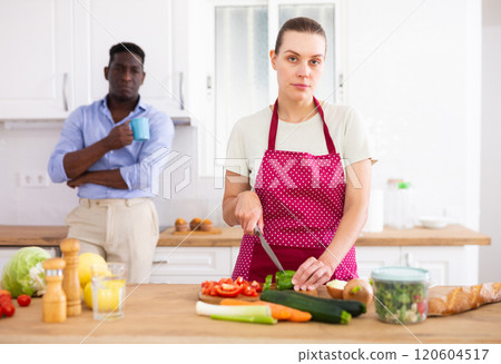 Pensive woman in apron cutting vegetables for vegetables at home 120604517