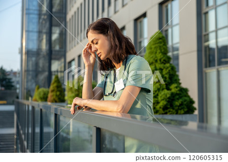 Young female doctor standing near clinic and feeling tired Young female doctor standing near clinic and feeling tired 120605315