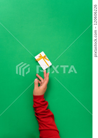 Holiday-themed concept with woman hands showcasing a gift or shopping card. Minimalistic design with woman hands holding a plastic card for Christmas or celebrations 120606226