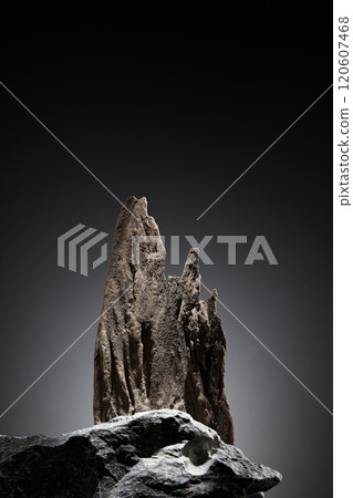 A minimalist template picture with a frontal view of a rugged, large stone block with an empty space to display a product, behind it is a rock standing like a tower in the gradient dark background. A minimalist template picture with a frontal view of a rugged, large stone block with an empty space to display a product, behind it is a rock standing like a tower in the gradient dark background. 120607468