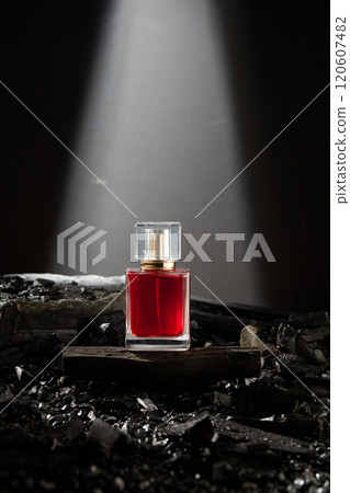 A perfume glass bottle mockup, with a red liquid inside placed on a charcoal block, surrounded by coal pierce and hardwood charcoal block on the surface. Template ads for product with coal ingredients A perfume glass bottle mockup, with a red liquid inside placed on a charcoal block, surrounded by coal pierce and hardwood charcoal block on the surface. Template ads for product with coal ingredients 120607482