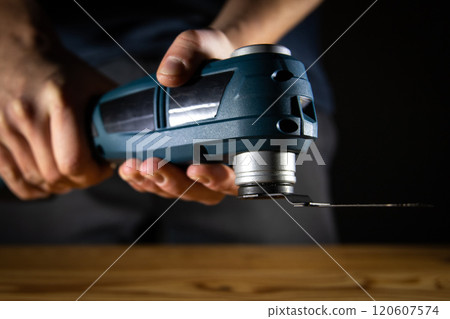 A hand gripping a powerful multi cutter tool, ready for cutting tasks, highlighting its ergonomic design and blade. 120607574