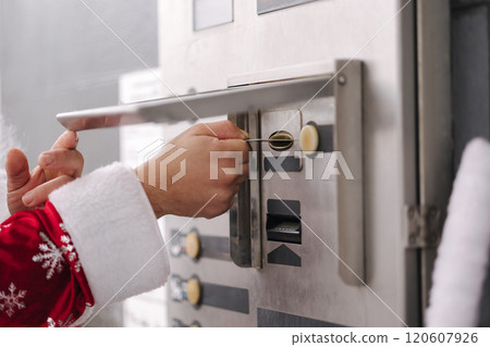 Santa inserting a card into a vending machine. Highlights a blend of traditional holiday character and everyday modern interaction. 120607926