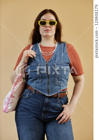 Vertical portrait of modern young woman with curvy figure wearing denim and funky sunglasses outdoors Vertical portrait of modern young woman with curvy figure wearing denim and funky sunglasses outdoors 120608179