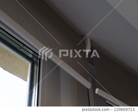 Intermediate bracket that holds two blinds together. Roller blinds close up on the window. The distance between the fabrics when installing roller shades end-to-end. Motorized curtains. Intermediate bracket that holds two blinds together. Roller blinds close up on the window. The distance between the fabrics when installing roller shades end-to-end. Motorized curtains. 120608723