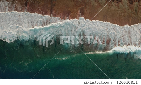 Dramatic green water waves crashing on sand beach coast. The stunning colors of the powerful storm ocean foam splashing volcanic surface seascape. Natural background. Aerial drone shot top down view 120610811