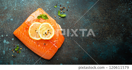 Fresh raw salmon marbled fillet on dark blue rustic concrete table background with lemon, coarse salt, green herbs top view. Healthy cooking and balanced diet 120611579