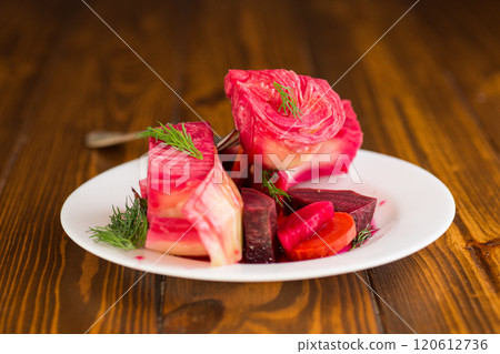 pickled cabbage with beets and carrots, in a plate, on a wooden table 120612736