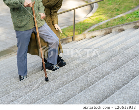 Senior couple: man climbing stairs with a cane and woman supporting him 120612938