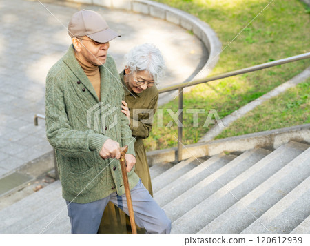Senior couple: man climbing stairs with a cane and woman supporting him 120612939