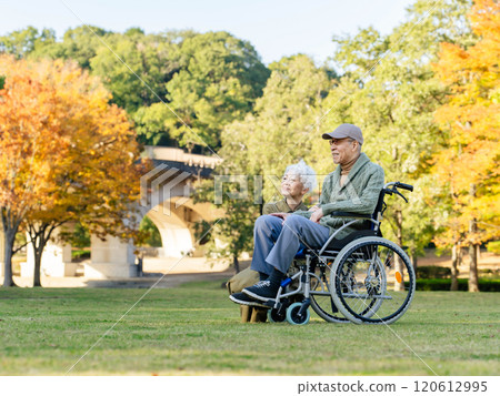 坐在輪椅上的老夫妻抬頭望著公園裡的天空 120612995