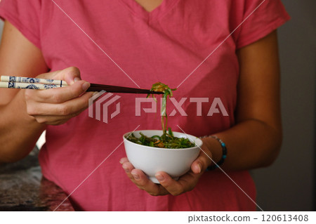 Girl holding a cup of wakame in her hands Girl holding a cup of wakame in her hands 120613408