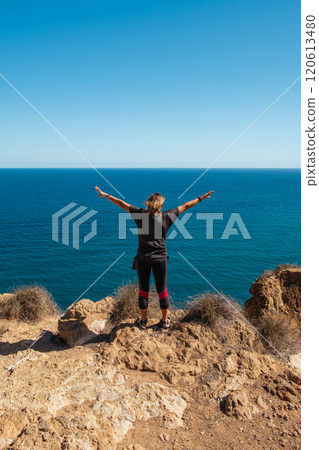 Girl standing on the edge of a cliff with outstretched arms Girl standing on the edge of a cliff with outstretched arms 120613480