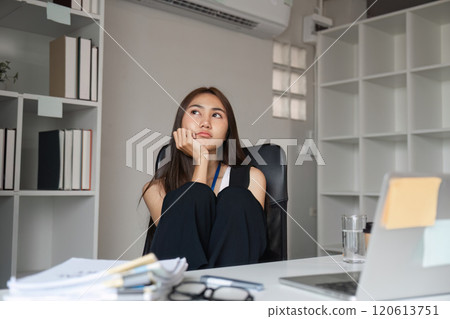 Bored Woman at Work Desk in Modern Office Setting with Laptop and Documents 120613751