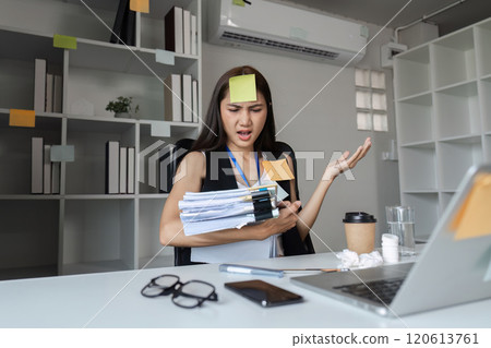 Focused Businesswoman Multitasking at Desk with Documents, Laptop, and Coffee in Modern Office Environment 120613761