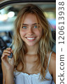 Caucasian woman showing car keys in hand sitting inside car in showroom. 120613938
