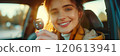 Caucasian woman showing car keys in hand sitting inside car in showroom. 120613941