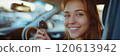 Caucasian woman showing car keys in hand sitting inside car in showroom. 120613942